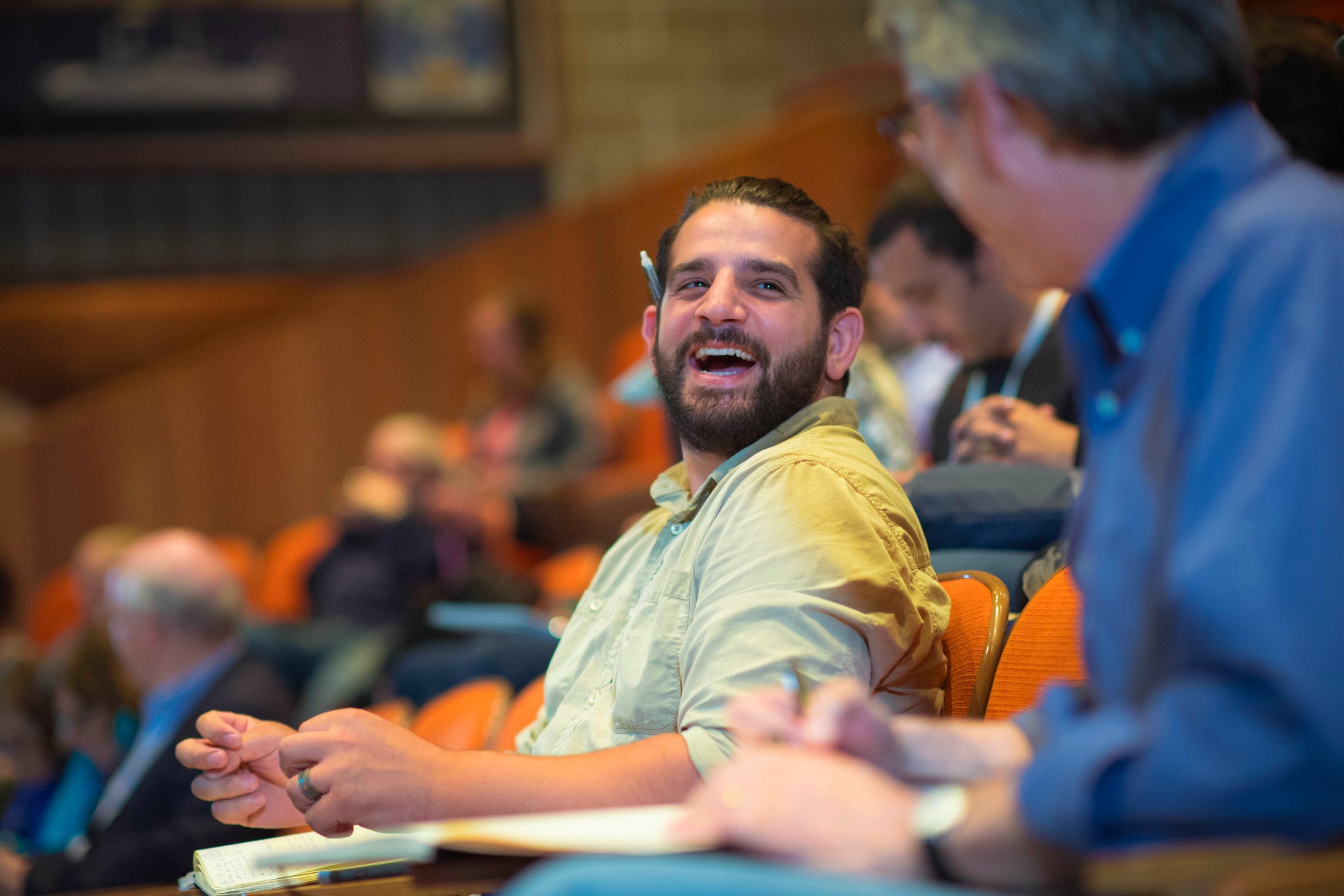 Person sitting in an auditorium and smiling at another