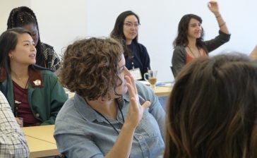 Photo of several women raising their hands in a classroom